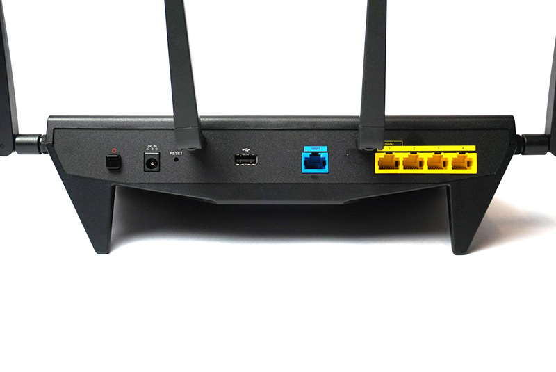 背面。高い後ろ脚で床面から大きく離れている。左から電源ボタン、WAN、USB 3.0ポート、WAN＆LAN兼用、LAN×3