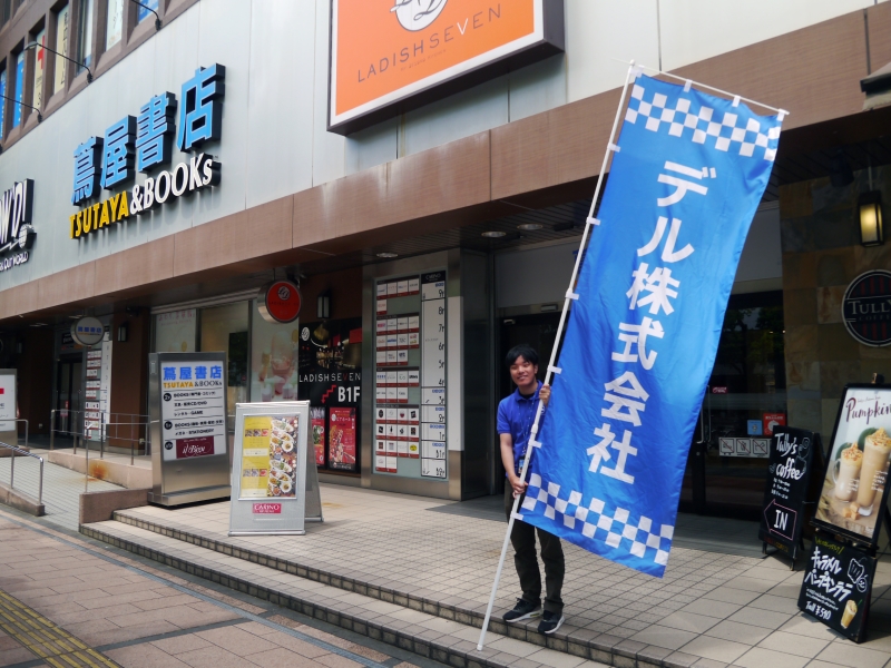 ビルの外では社員が旗を持って出迎えた