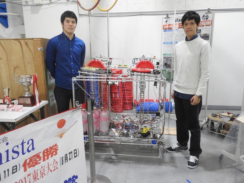チームMaquinistaが製作したロボット「雅」を挟んで立つ徳田氏と野田氏