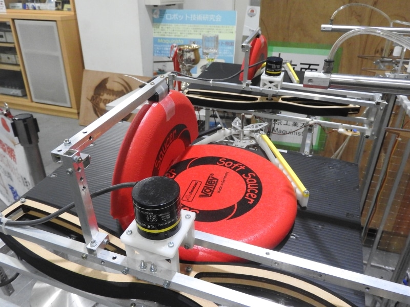 下からせり上がってきたディスクを奥にみえるハンドで射出機構まで運び、セットする