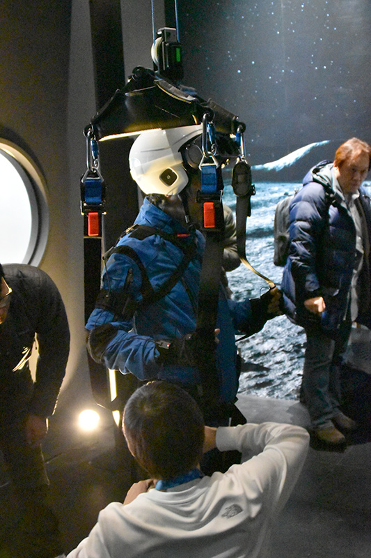 世界初公開となる宇宙空間のVR体験。スーツを着て、ハーネスで宙づりになり、体にとりつけた各種のセンサー類で月面の重力状態を体験できる