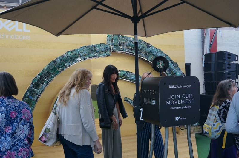 最近米国のイベントでよく見かける自撮りマシンのコーナー。写真を撮影してその場で、印刷して来場者に渡すシステム。そのアーチは、過去の基板から構成されていた。チップやボードの型番などは消されていたのだが、なぜか競合他社のロゴは消されていなかった……