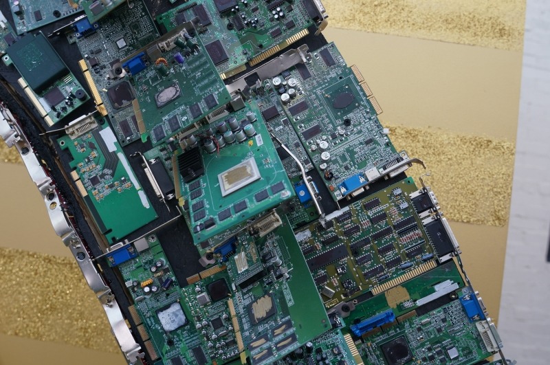 最近米国のイベントでよく見かける自撮りマシンのコーナー。写真を撮影してその場で、印刷して来場者に渡すシステム。そのアーチは、過去の基板から構成されていた。チップやボードの型番などは消されていたのだが、なぜか競合他社のロゴは消されていなかった……