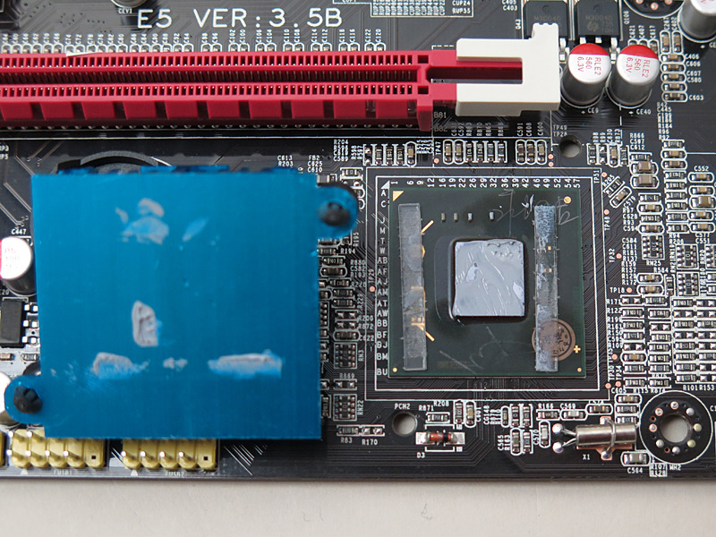 チップセットのヒートシンクを外したところ。グリスがたっぷり塗られているが、まったく接触していない。そしてサブストレート上の金のパターンが怪しい。というか、誰のサインですか……