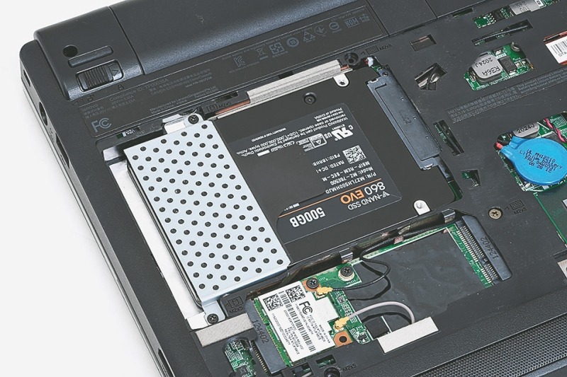 ⑧SSDをノートPCに組み込む<br>SSDを2.5インチベイに挿し込み、2本のネジで固定する。あとは底面のカバーをもとに戻す。これでSSDから起動が可能になる