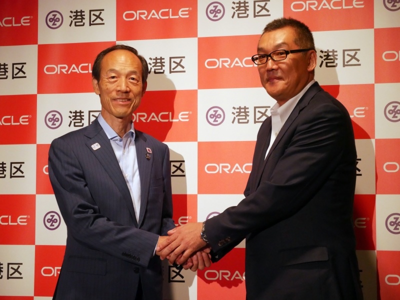 握手する東京都港区の武井雅昭区長(左)と日本オラクル 専務執行役員 公共営業統括の白石昌樹氏(右)