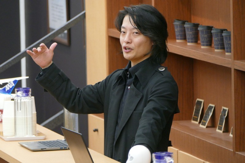 カフェのカウンターのなかでプレゼンする吉藤健太朗氏