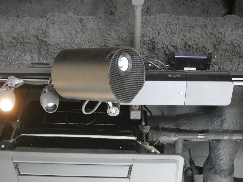 レーザー光源搭載ライティングモデルを使用して、鈴村社長の顔写真を壁面に投影する演出も行なわれた