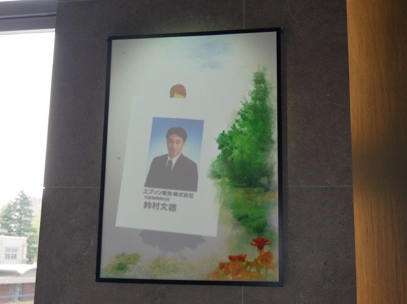 レーザー光源搭載ライティングモデルを使用して、鈴村社長の顔写真を壁面に投影する演出も行なわれた