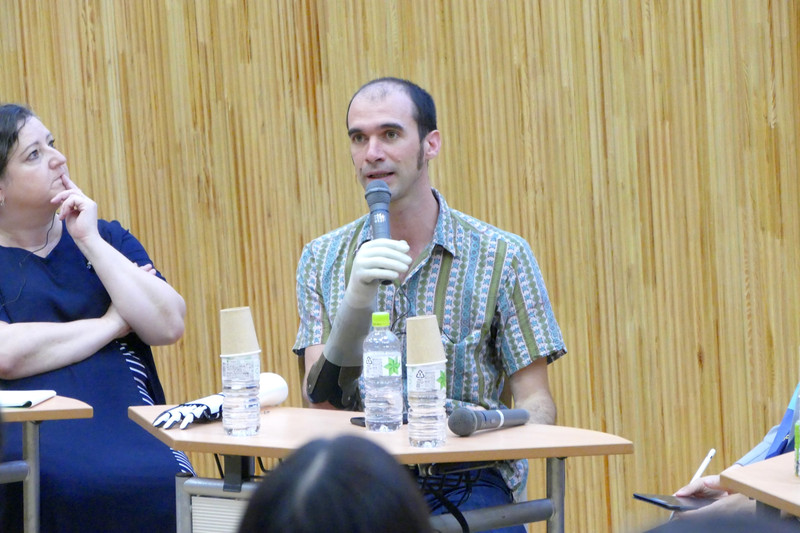 筋電義手でマイクを握ってプレゼンを行なうニコラ・ユシェ氏