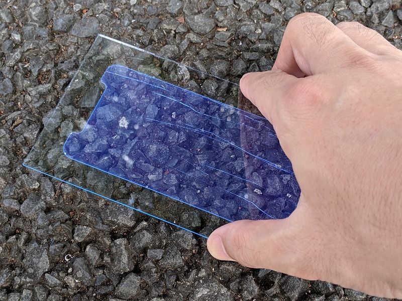 荷重をかけつつアスファルト面を滑らせて傷の程度をチェックする(実際のテストでは手で押さえるのではなく上におもりを乗せて検証している)