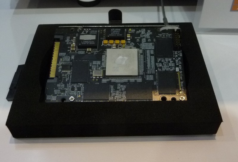 試作したSSDとその実装基板。両面基板に128Gbitの「XL-FLASH」メモリを8個搭載している。基板の中央にある銀色のチップがコントローラ。FMSの展示ブースで筆者が撮影したもの