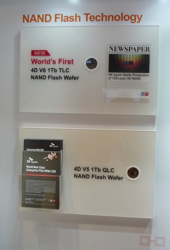 1Tbitフラッシュメモリを作り込んだシリコンウェハの展示。上が第6世代(V6)技術とTLC方式の組み合わせで開発したシリコン、下が第5世代(V5)技術とQLC方式の組み合わせで開発したシリコン。いずれも小さな円形の窓を通じてのみ、シリコンウェハが見える。FMS展示会場のSK Hynixブースで筆者が撮影したもの