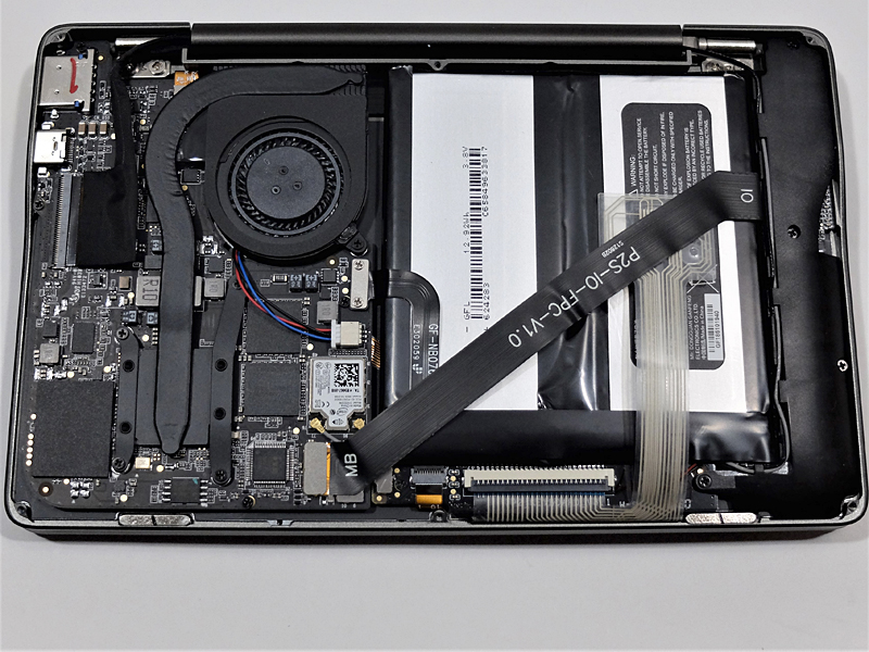 底面カバーを外したところ。インターフェイスとマザーボードを繋ぐフラットケーブルが内蔵バッテリの上に被さる形で配置されている。カバーは底面の6個のネジを外すことで着脱可能