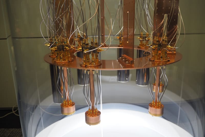 実際はこの銅でできた円筒の下に量子デバイスが貼りつけられる。現在検証中の量子アニーリングマシンは、1つの量子デバイスで4量子ビットを実現しているため、これ全体ではその円筒が8個あるため(手前はわかりやすいように金属の円筒カバーが外されているが、実際は奥にあるように円筒カバーで覆われている)、32量子ビットになる