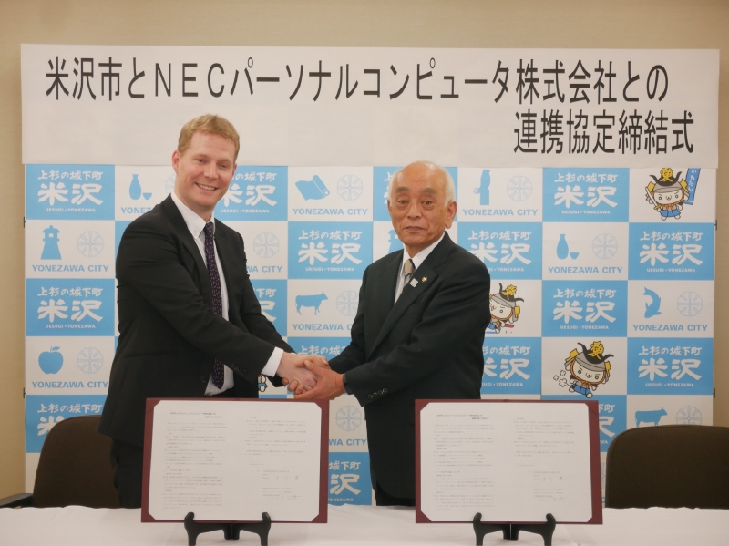 締結式での米沢市の中川勝市長(右)とNECパーソナルコンピュータのデビッド・ベネット社長(左)