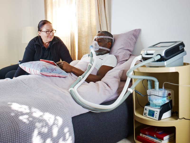 ResMedの人工呼吸器「Astral 150」(写真右側)を装着した患者。Infineon Technologiesの2020年4月9日づけニュースリリースから