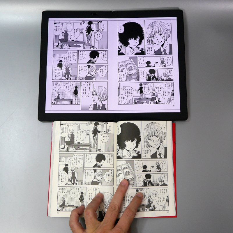 紙の単行本との比較。テーブルの上に置いても（ほぼ）完全にフラットにでき、また紙の本のように手を離しても閉じないのは利点だ