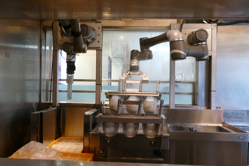 左のアームがそばを番重から取出し、右のアームが茹で、締めを行なう