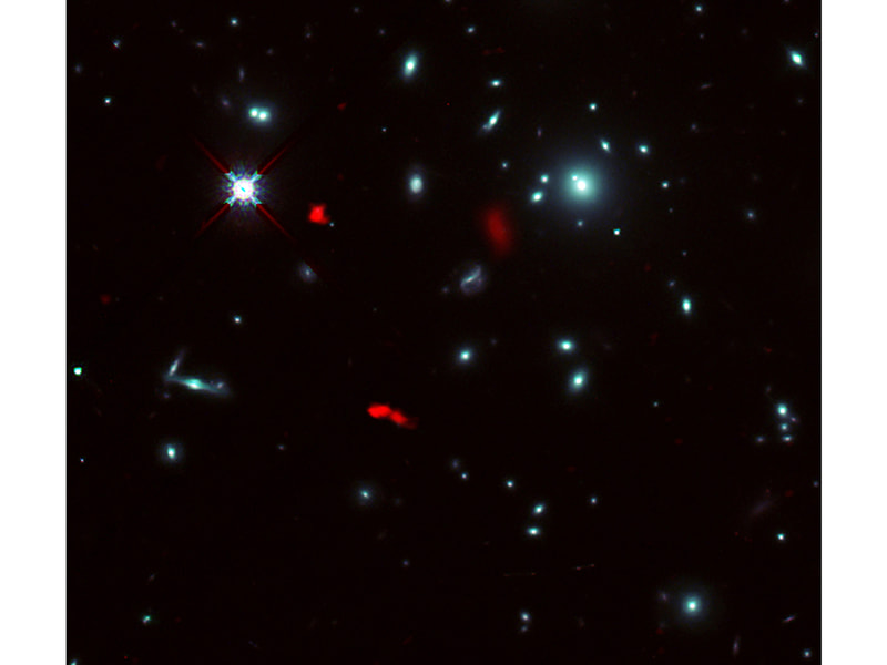 ハッブル宇宙望遠鏡が撮影した銀河団RXCJ0600-2007の画像に、アルマ望遠鏡で観測した129億光年彼方の銀河RXCJ0600-z6の重力レンズ像を赤色で合成した画像