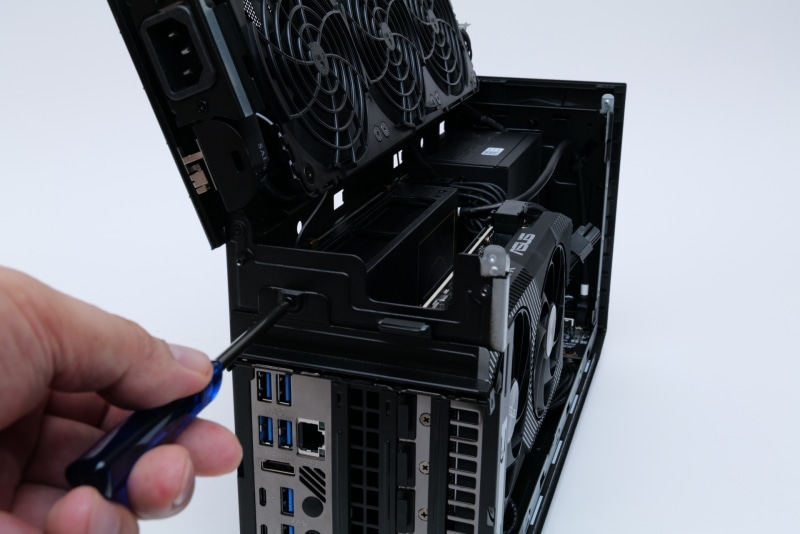 背面の左上のプラスネジをはずすと、拡張カードのネジを隠しているカバーを手前に開ける