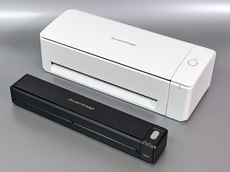 ScanSnap iX100(手前)と本製品の比較。iX100はスリムでモバイルにも向くがスキャンは片面ずつ、かつ1枚ごとにしか行なえない