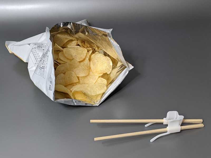 「ゲーミング割りばしホルダー」に割りばしを装着した状態。手を汚さずにポテトチップスなどをつまむのに重宝する。実売価格は1,210円