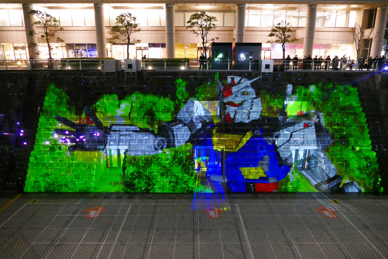 投影映像の最後のシーン。ガンダムの手から光の粒が放たれる<br>© 創通・サンライズ