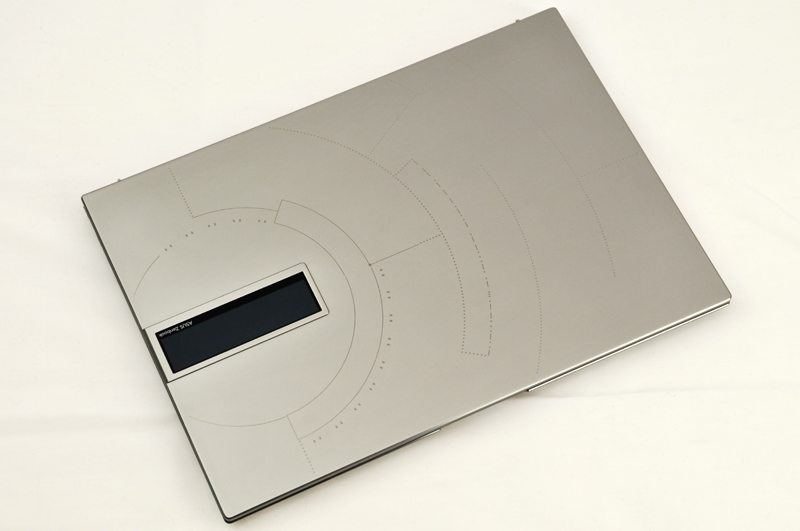 宇宙カプセルをイメージしているという天板の図形。写真の左上が本体の奥側で右下が手前側だ。中央の少し右にある縦の曲線が「Ad Astra Per Aspera」のモールス信号である。困難を乗り越えて星々へという意味が込められている