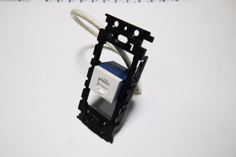 取り付け用ステーにLANコンセントを固定。樹脂製だとはめ込むだけ。金属製だとマイナスドライバーでかしめる