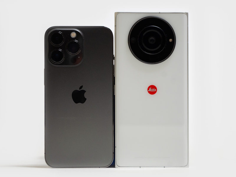 背面(iPhone 13 Proとの比較)。色はホワイト。上側にカメラユニット。中央辺りにLeicaのロゴ。iPhone 13 Proと比較して、フットプリントはパネルサイズ分大きい