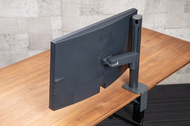 デスク奥側ぎりぎりまで寄せても、アームはデスクからほとんどはみ出ない。壁際でもモニター位置を追い込める