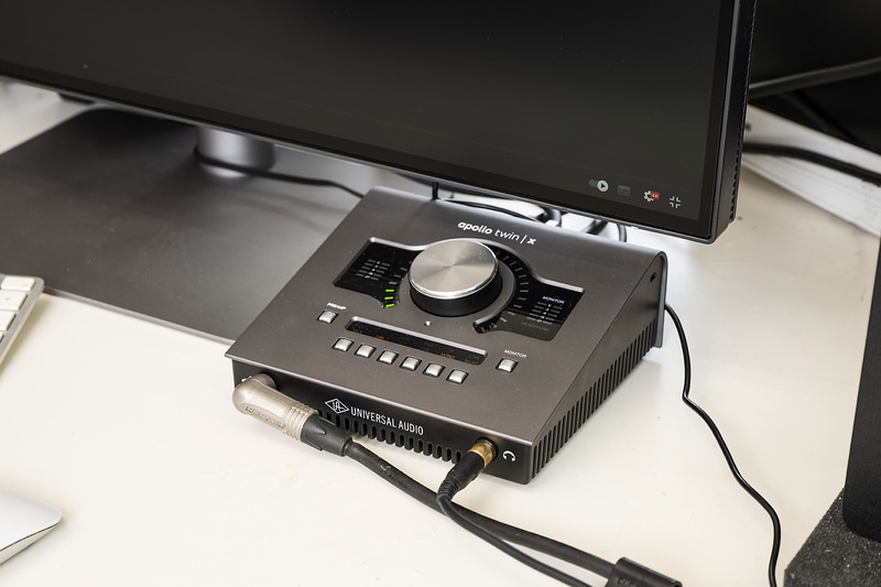 iMacからモニターを経由してオーディオインターフェイスをつなぐことで、使いやすい場所に設置でき、ケーブル由来のノイズ発生も抑えられたという