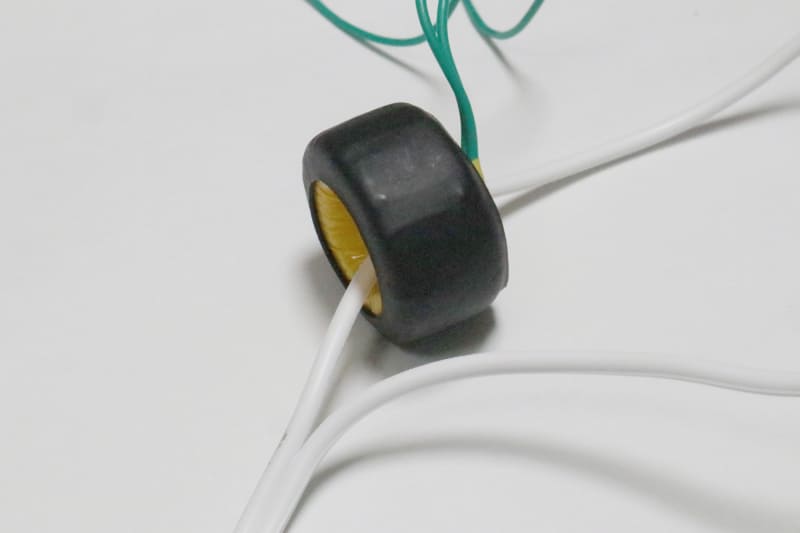 白い電線がコンセントの電源ライン。2本のうち片方の電線だけコイルをくぐらせる