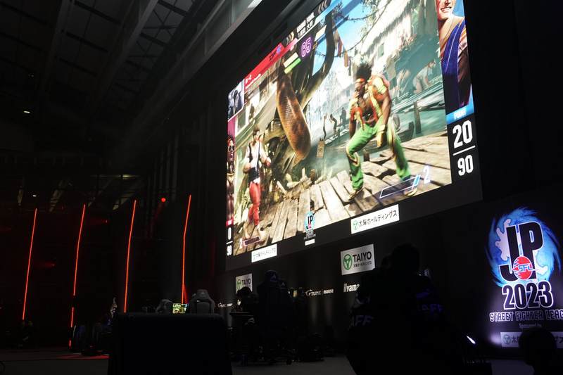 試合中のステージの様子。ステージ奥の大型スクリーンに試合の様子が映し出されている
