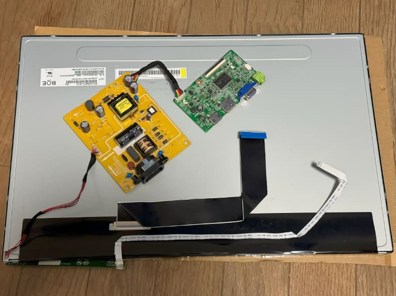 液晶パネルの上にAC-DCコンバータ基板(茶色)とLCDコントロール基板(緑色)載っている状態(AC-DCコンバータ基板で感電しないよう注意すること)