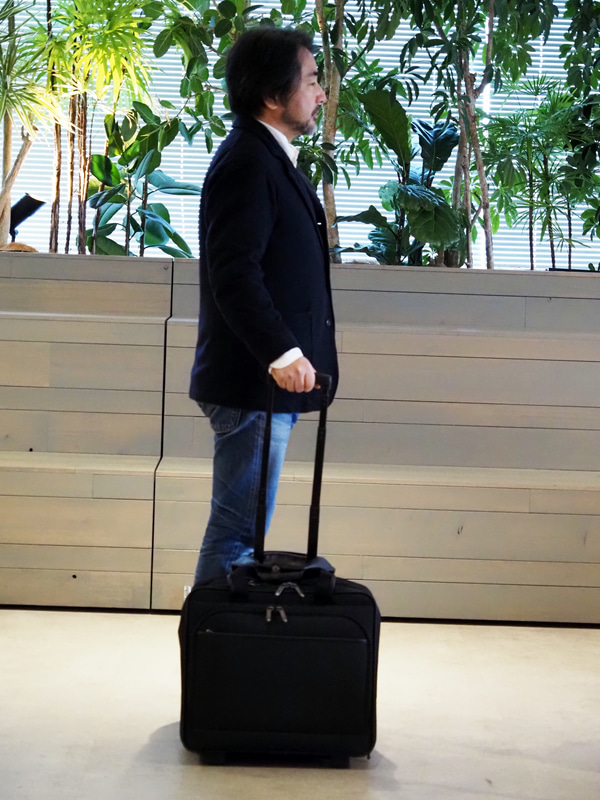 身長168cmの筆者が持ったところ。大型2輪キャスターは動きがよく荷物を詰め込んでもスムーズに動くが、4輪と比べると細かくは取り廻せない。ただし、2輪の場合はストッパーが装備されているので、不意に動いたりしないというメリットがある