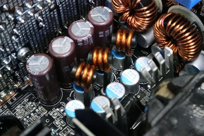 2次側平滑回路は、電解コンデンサとコイルで形成される。高価な電源だと「アルミ固体コンデンサ」も併用される。写真では茶色が電解コンデンサ、青い印刷がある小さい円筒がアルミ固体コンデンサ。導線が3周巻いてあるのはチョークコイルと呼ばれるもので、これも滑らかに平滑するのに重要な部品