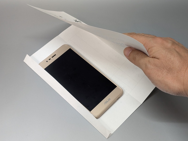 申込書の印字面が外になる状態で、スマホを包むようにしてテープ留めする