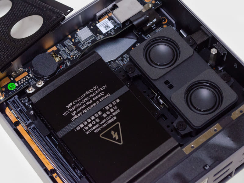 ここからが大変。写真、電源ユニット左上の銀色のネジ2本、ユニットを固定するシール、ユニット右側にあるネジ2本、ユニットの下にネジ3本、スピーカー中央上にある六角柱……これらをすべて外す