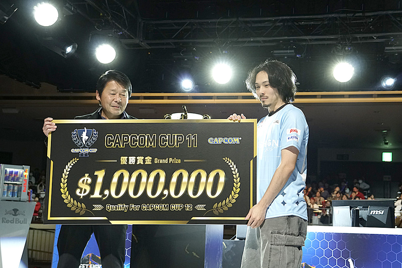 賞金総額100万ドルのパネルをカプコンの辻本春弘代表取締役社長執行役員・COOより受け取る