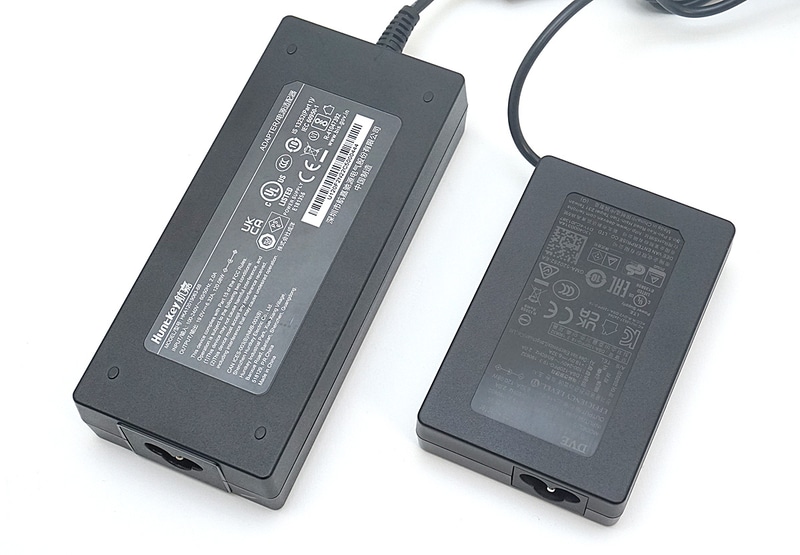 別のミニPCに付属する120W出力対応のACアダプタ(左)と比べると、やはり小さい