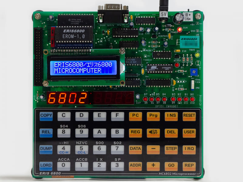 製品写真(表)。下側にパネル式の16進キーボード。その上にディスプレイ郡。上部に電源入力、スピーカーオン/オフスイッチ。左側に40ピンコネクタ