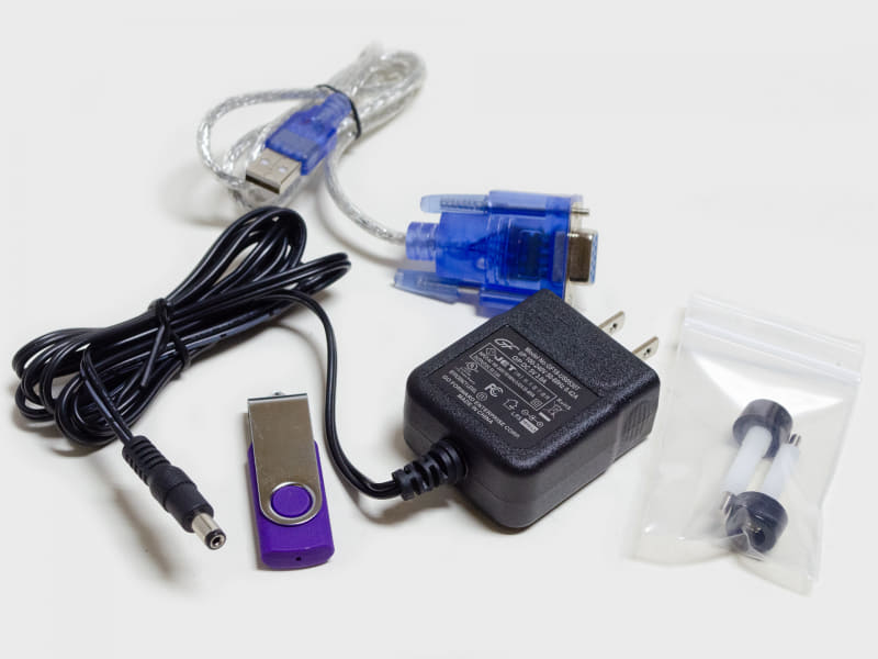 付属品。ACアダプタ(5V/3A)、USB/RS-232C、I/O基板・周辺基板取り付け用のプラ足付スペーサー×2、PDF版のマニュアル(USBメモリ)