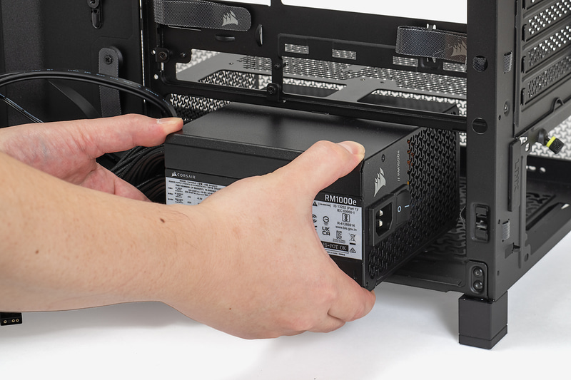 電源ユニットのファンを下側にして、右側面からPCケース内部に入れていく。ケーブルの数が多いので手でまとめながら入れていこう