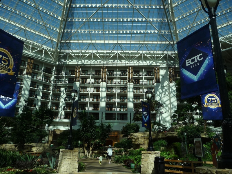 「Gaylord Texan Resort & Convention Center(ゲイロードテキサスリゾートアンドコンベンションセンター)」の中庭(透明な天井を備えた巨大なサンルーム)。「ECTC 2025」ののぼりが右上に見える。米国時間5月27日に筆者が撮影