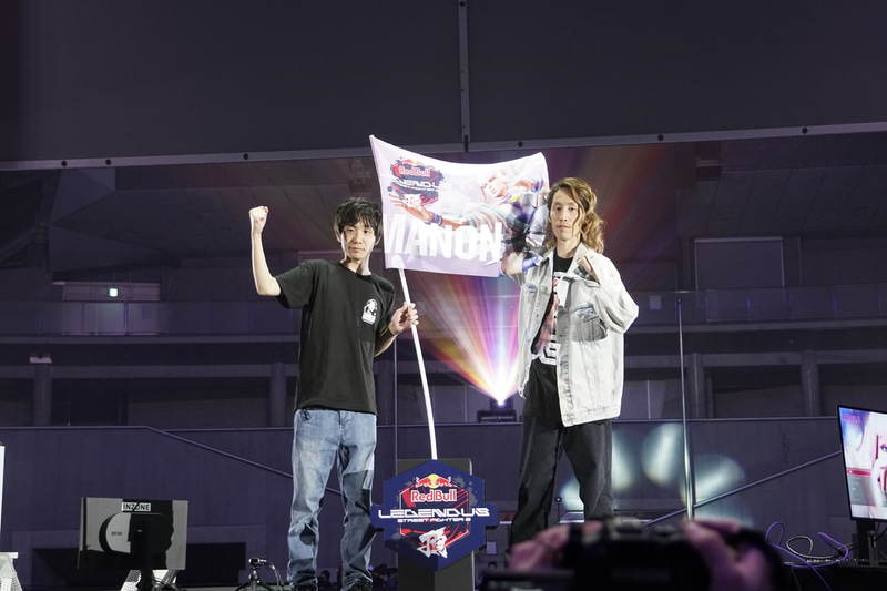 ステージに用意された頂にマノンの旗を立てる両氏