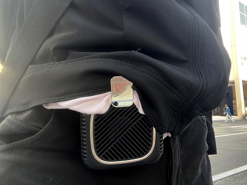 腰掛け扇風機の利用例。屋外での利用にはこのように銀のクリップで服の裾を止めることで吸気口の前を開けた状態で使用しないと空気が通らなくなってしまう。また装着時は排気口が服の最奥部、インナーのさらに内側に入るように固定するのがポイントだ