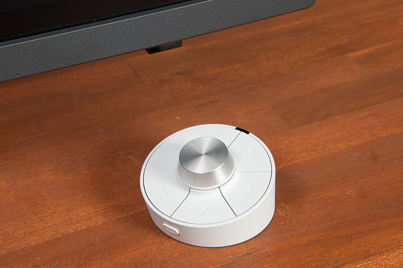 これがワイヤレスホットキーパック。中央にボタン付きのダイヤルコントローラ、その周囲に合計5個のボタン、手前側面に1個のボタンを備えており、個別に機能を割り当てることができる。