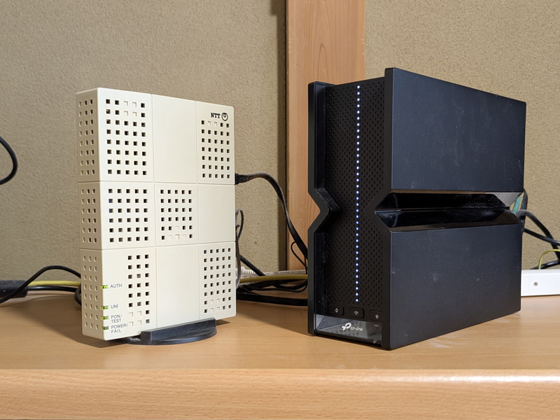 筆者宅の機器類。左がONUで、右がルーター(TP LinkのBE550)。戸建て住宅の場合、この2つの機器を室内のどこかに設置し、しかも24時間365日体制でコンセント電源動作させなければならない